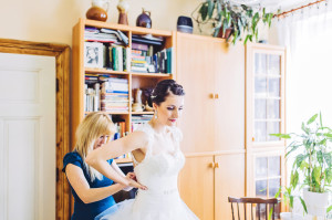 Kamarádka obléká nevěstě svatební šaty