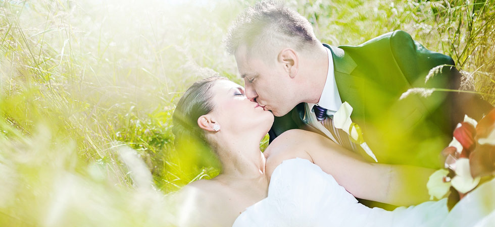 Nevěsta leží v trávě a ženich ji něžně líbá